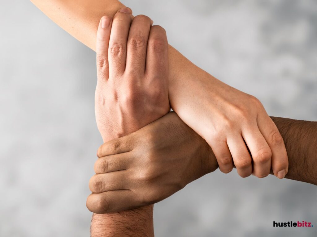 Three hands firmly clasp together.