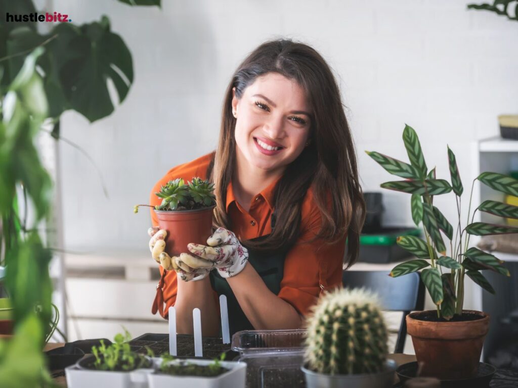 A woman happily holding a plant, surrounded by other greenery.