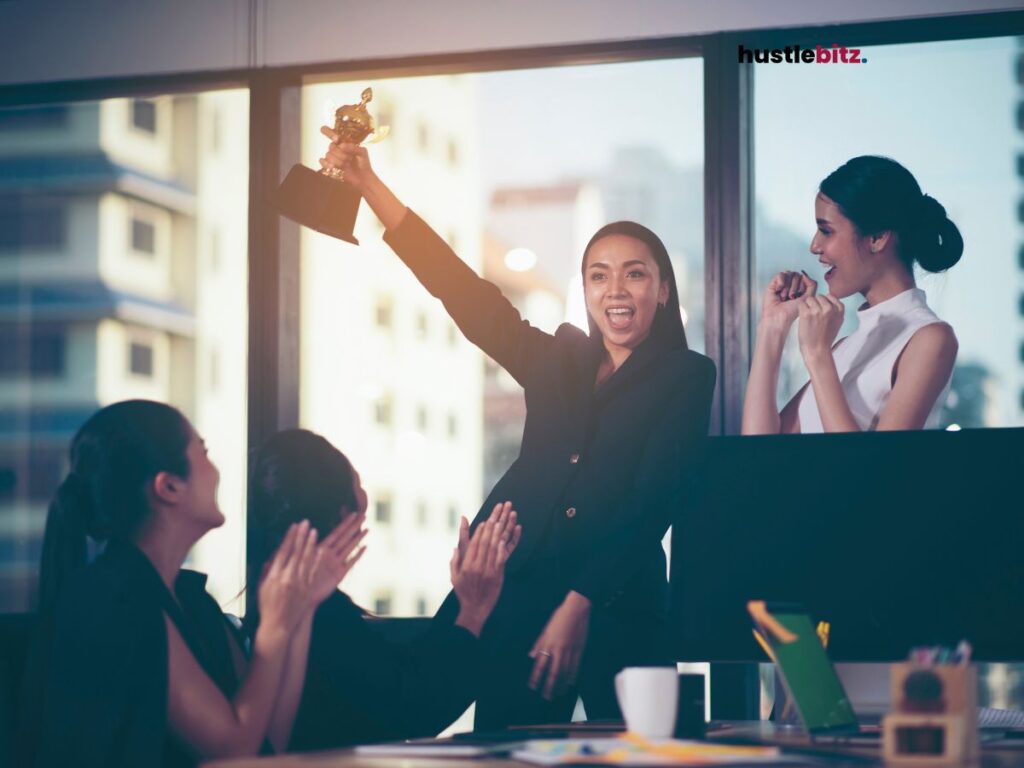 a group of woman clapping and smiles to the woman holding trophy