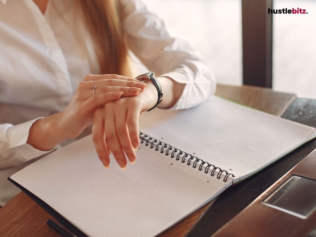 A woman hand wearing watch and a book in the table