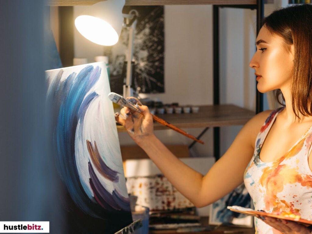 A woman painting an abstract artwork under a soft desk lamp.