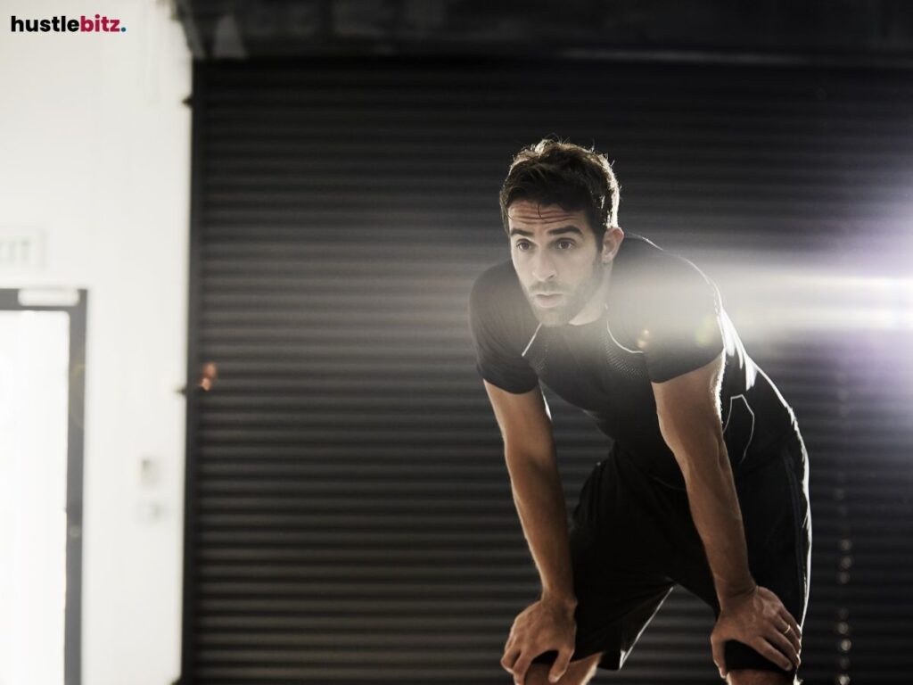 A man catching his breath after intense exercise, illuminated by light.