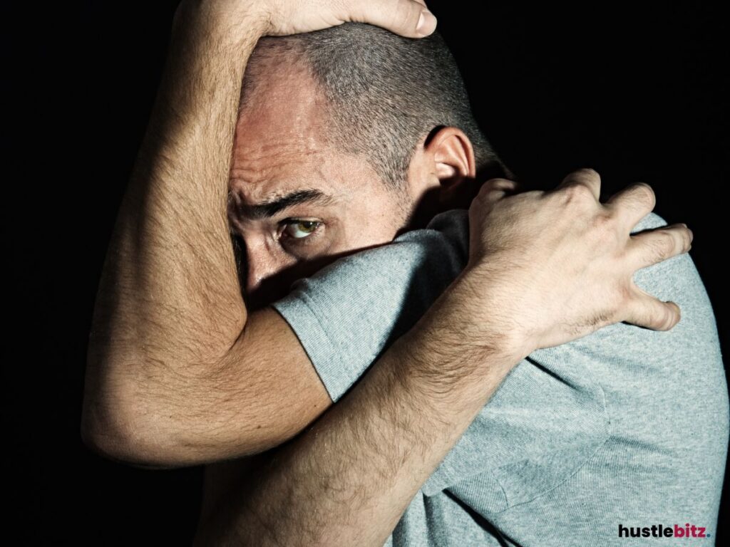 A man in a defensive posture, highlighting fear or anxiety.