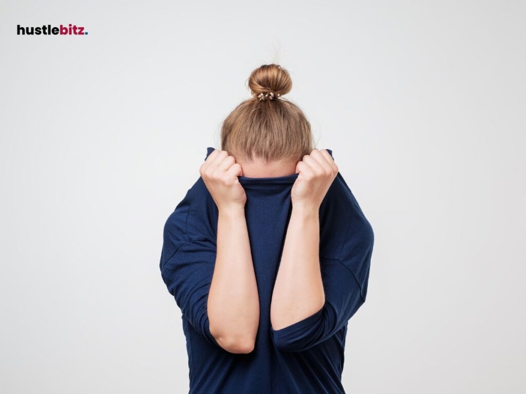 A woman hides their face with their shirt, conveying fear or anxiety