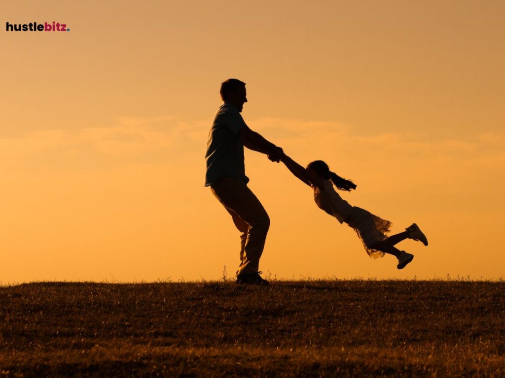 Silhouette of a father spinning his daughter at sunset.