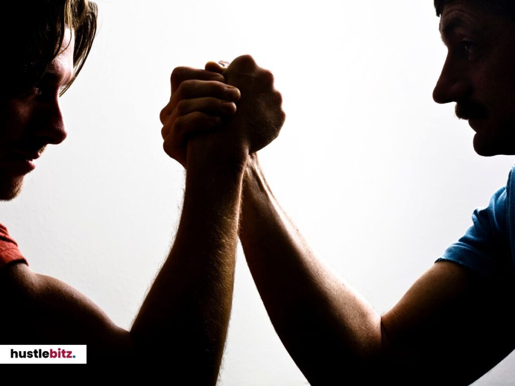 Two men arm-wrestling in a dramatic silhouette.