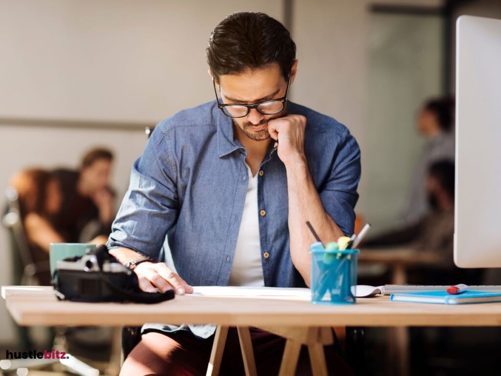 A man wearing eyeglass and a table with monitor