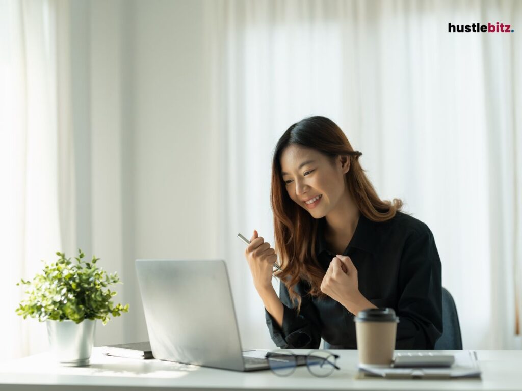 A woman smiles while looking at the laptop