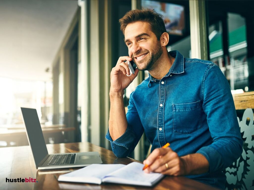 A man doing calling and a laptop in the table