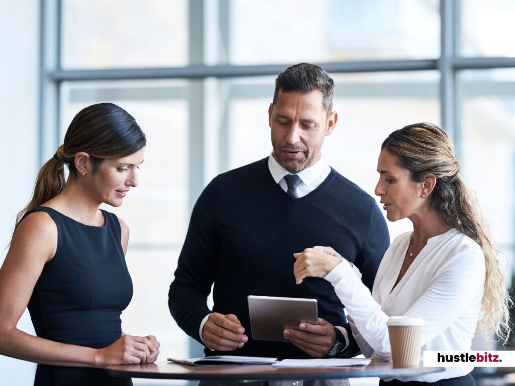 Three business professionals discussing work around a tablet.