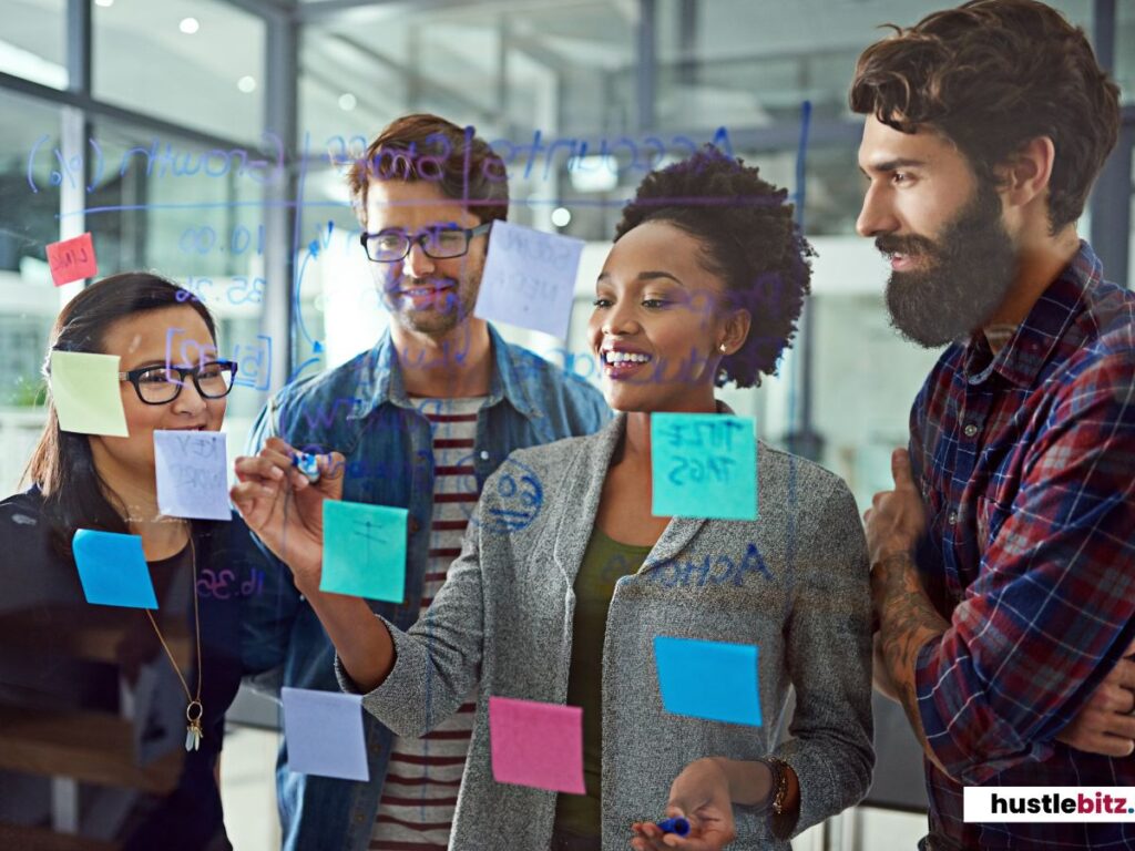 A team collaborates, writing ideas on a glass board with sticky notes.