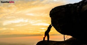 A person pushing a large boulder at sunset.