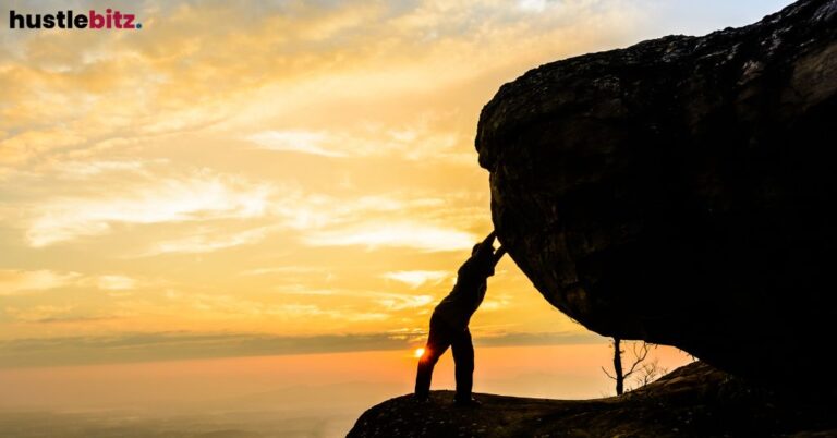 A person pushing a large boulder at sunset.