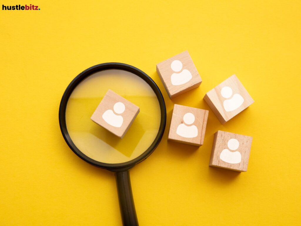 Magnifying glass examining wooden blocks with people icons on a yellow background.