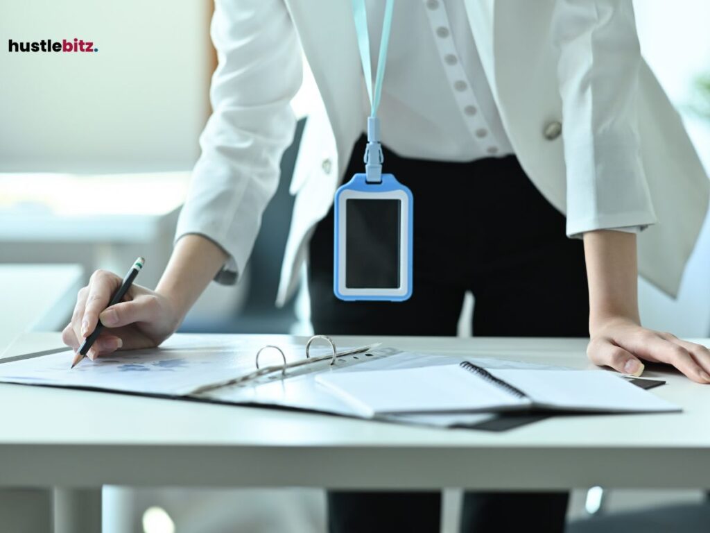 A woman in business attire leaning over a desk, writing notes on a document with a pencil. 