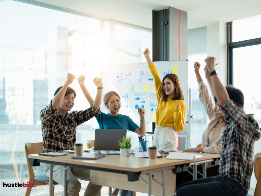 A group of people raise their hands representing victory in the word