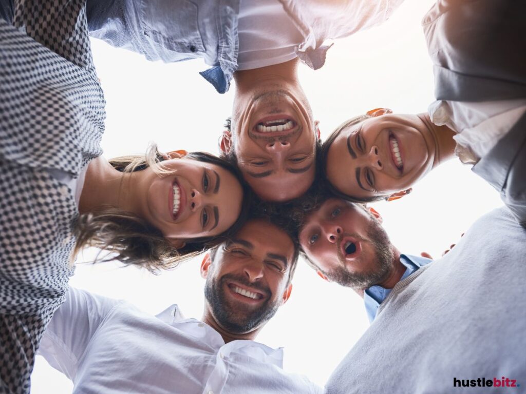A close-up group shot of five smiling friends huddled together.