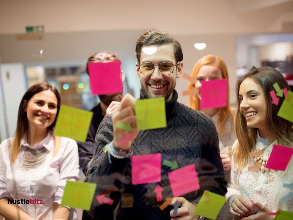 group of men and women smiles and the other men writing on sticky notes