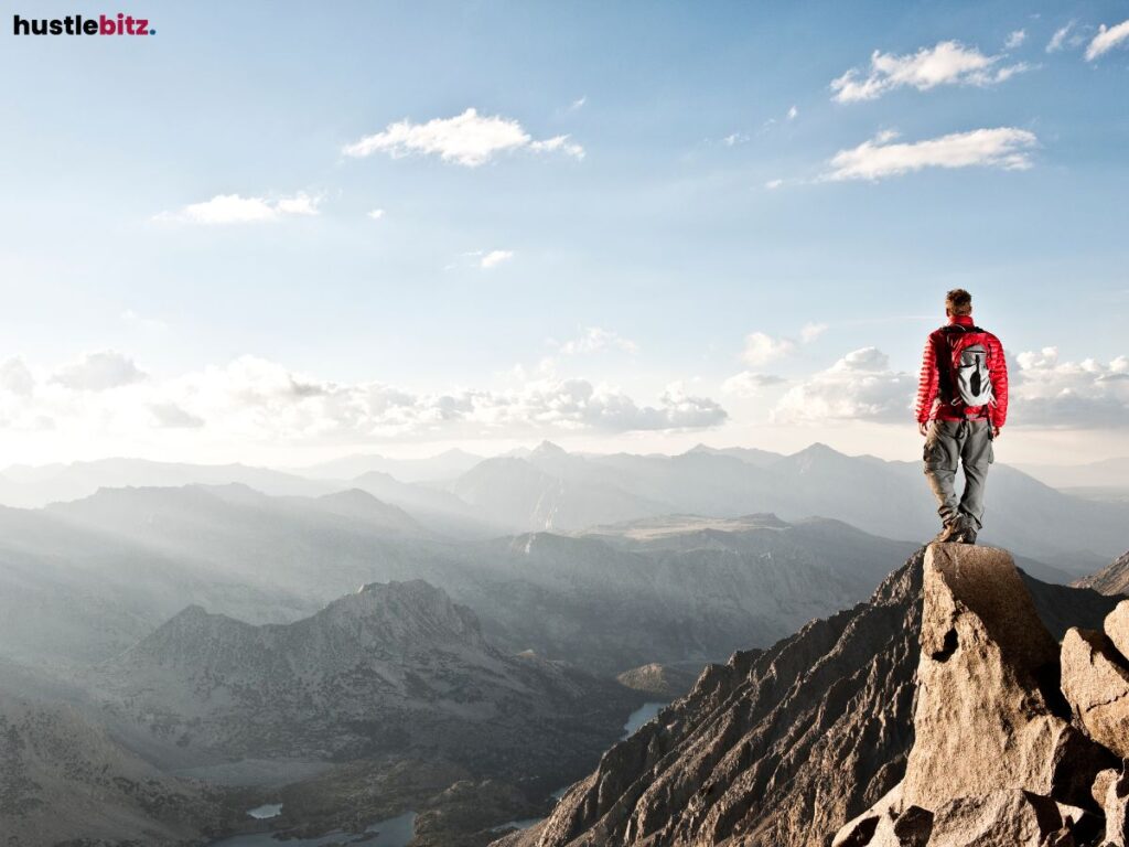 A person standing on a mountain ridge, gazing at distant peaks.