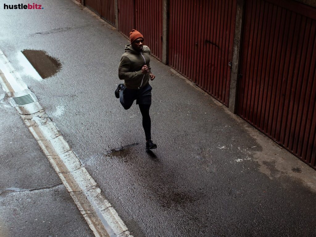 Man running through a narrow alley on a wet street.