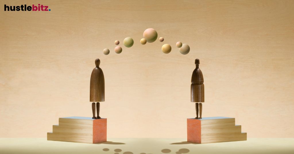 Two wooden figures on platforms exchange floating spheres.