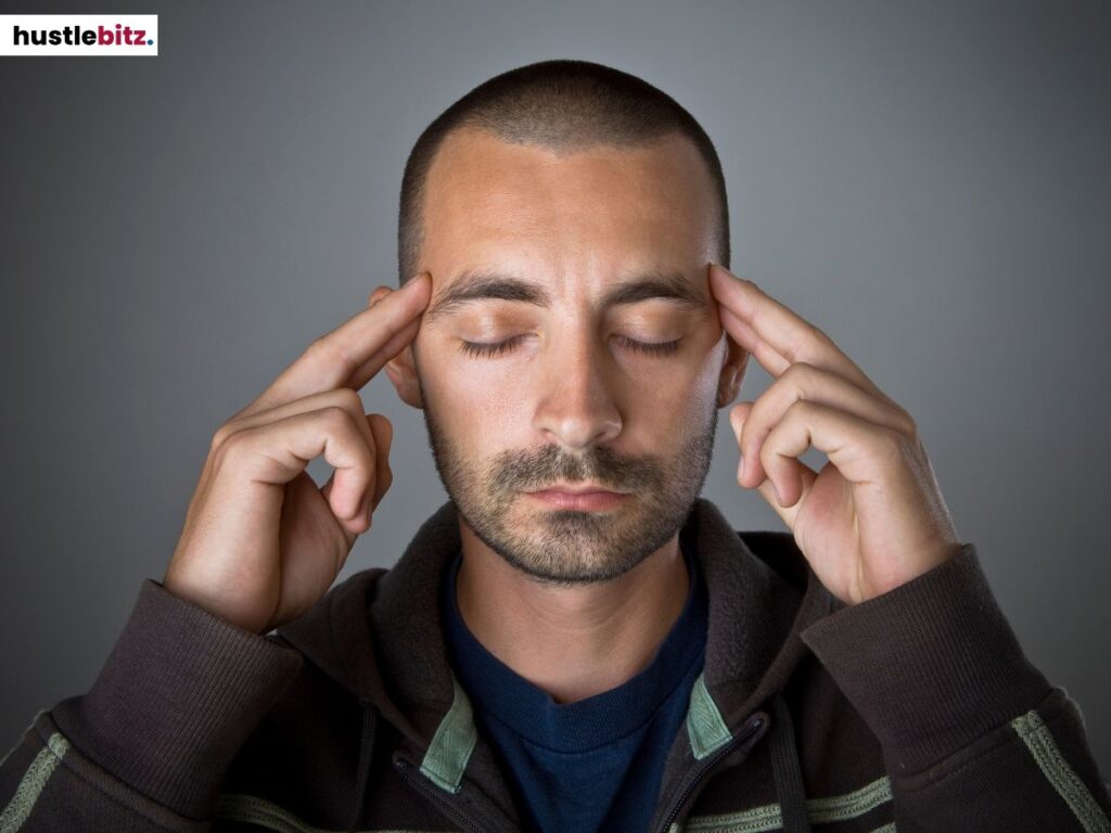 A man focused in meditation, pressing his fingers to his temples.