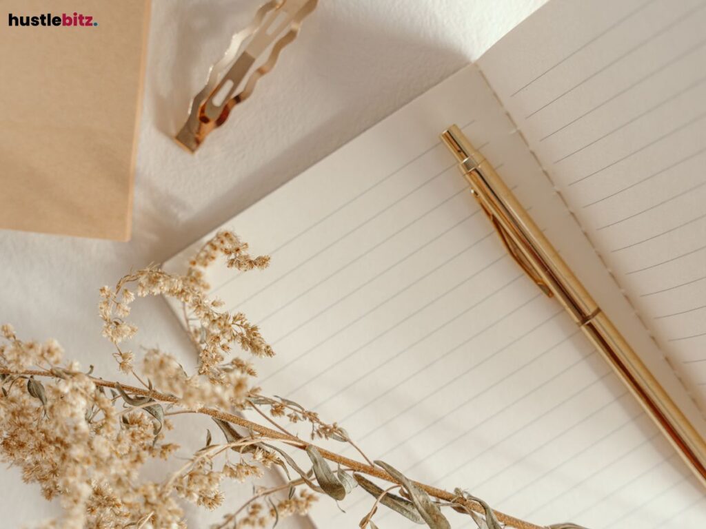 Open notebook with a golden pen, surrounded by dried flowers.