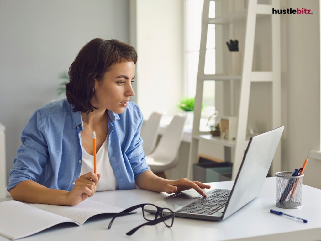 A woman doing writing and looking at the laptop inside the room