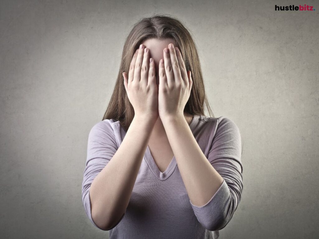A woman covering her face with both hands.