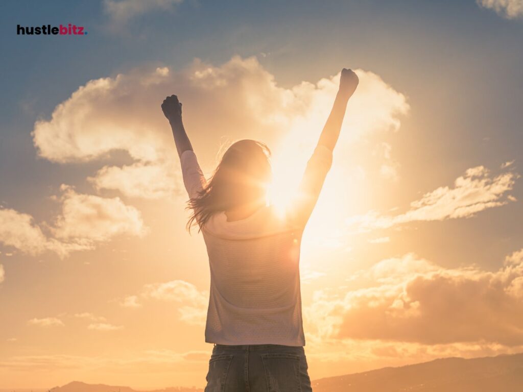 A woman up her to hands in front of sun and clouds