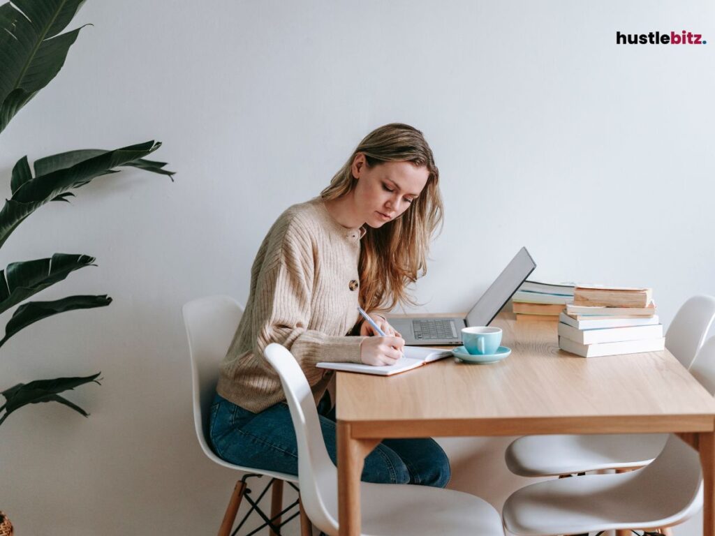 A woman doing writing in the table with laptop