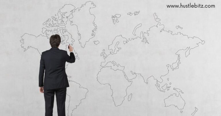 Man in a suit drawing a world map on a white wall.