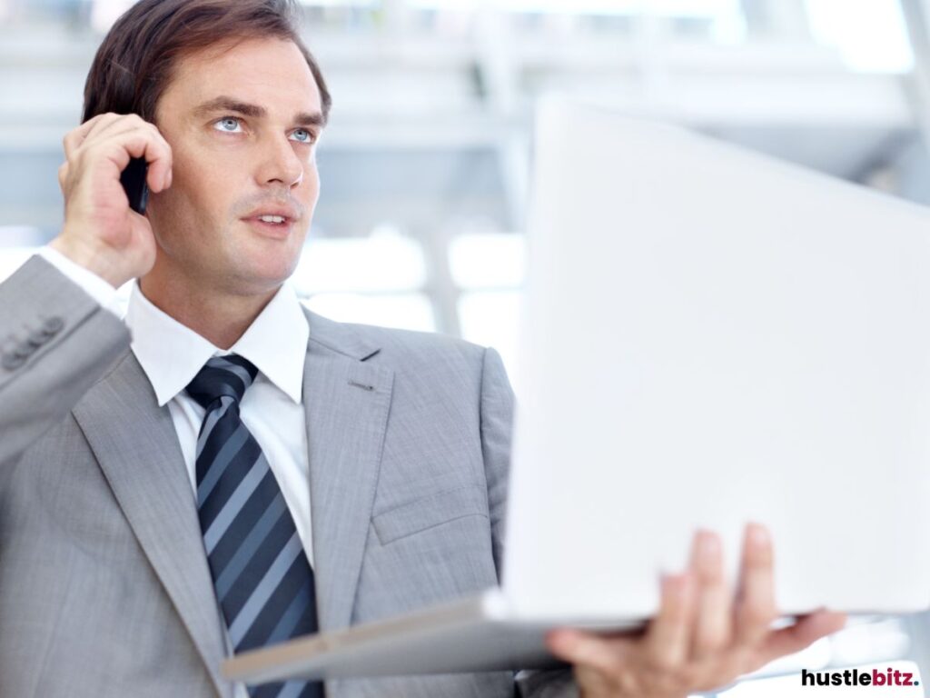 A businessman on the phone while holding a laptop, focusing on his tasks.