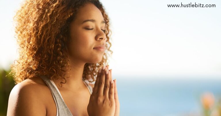 A woman meditates peacefully with her hands pressed together.