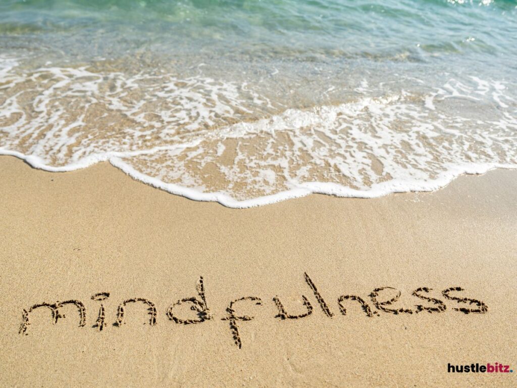 The word "mindfulness" written in the sand by the ocean.