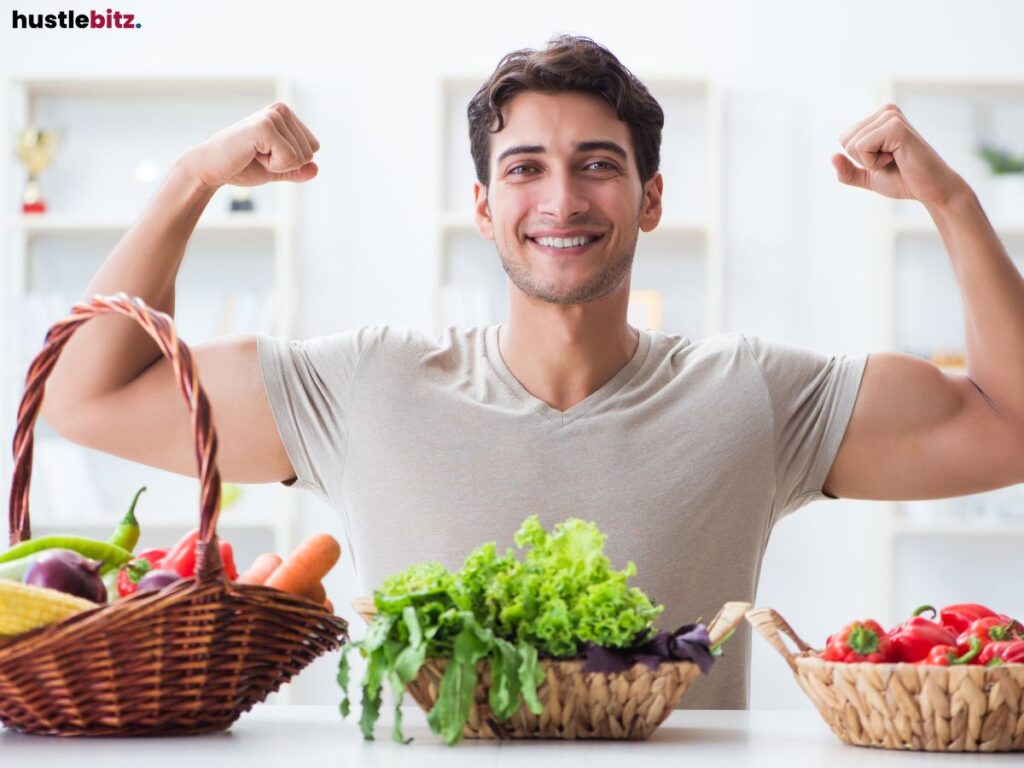 Happy man flexing his arms next to baskets of healthy vegetables.