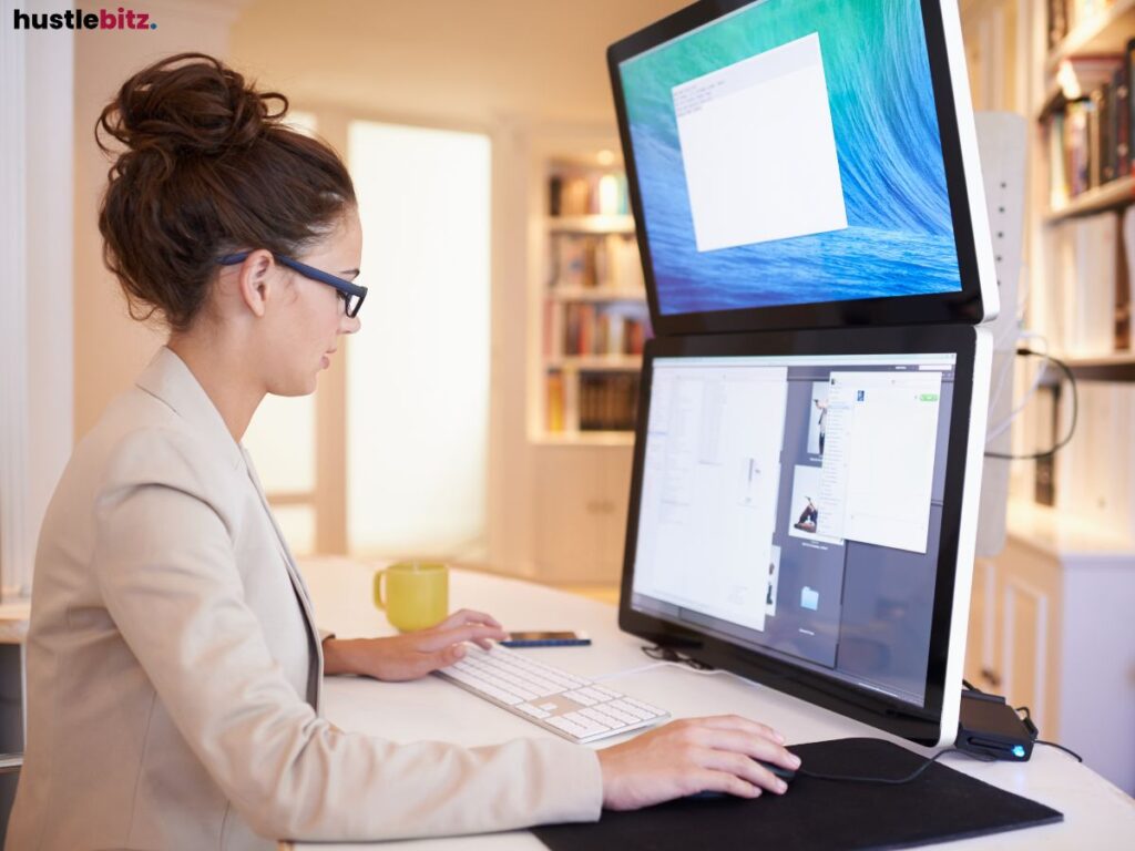 Woman working on a dual-monitor computer setup in a professional workspace.