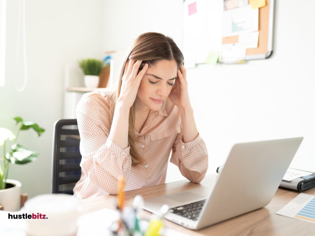 woman holding her head in front of the laptop