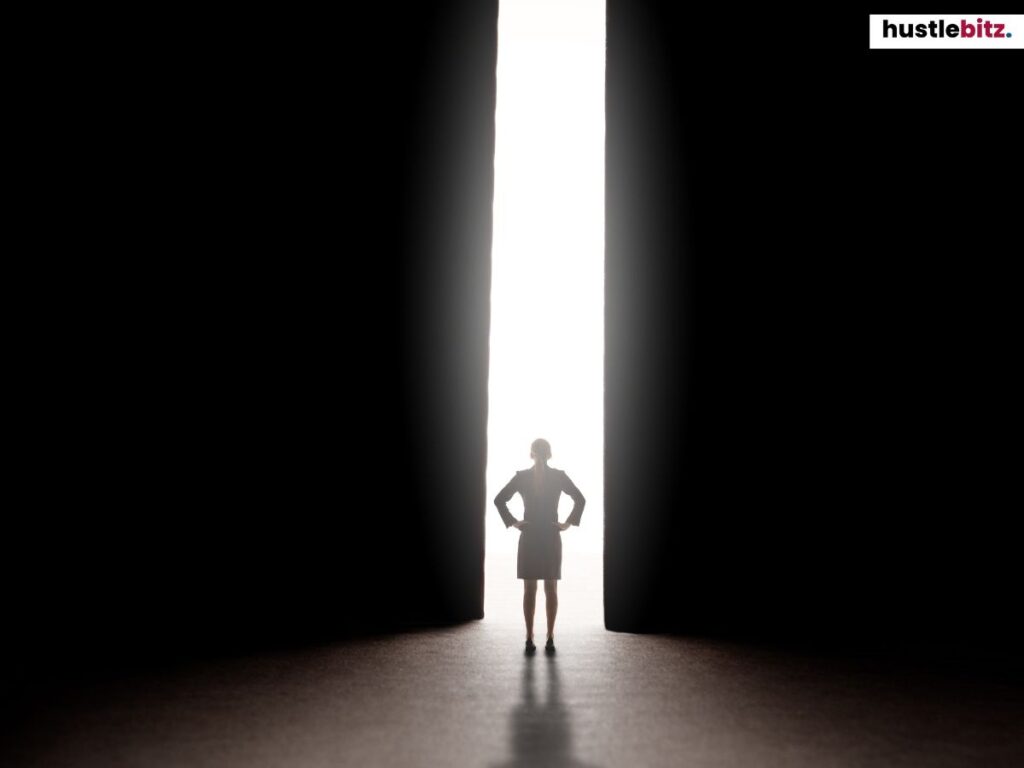 A woman silhouetted, standing confidently in a doorway filled with bright light.