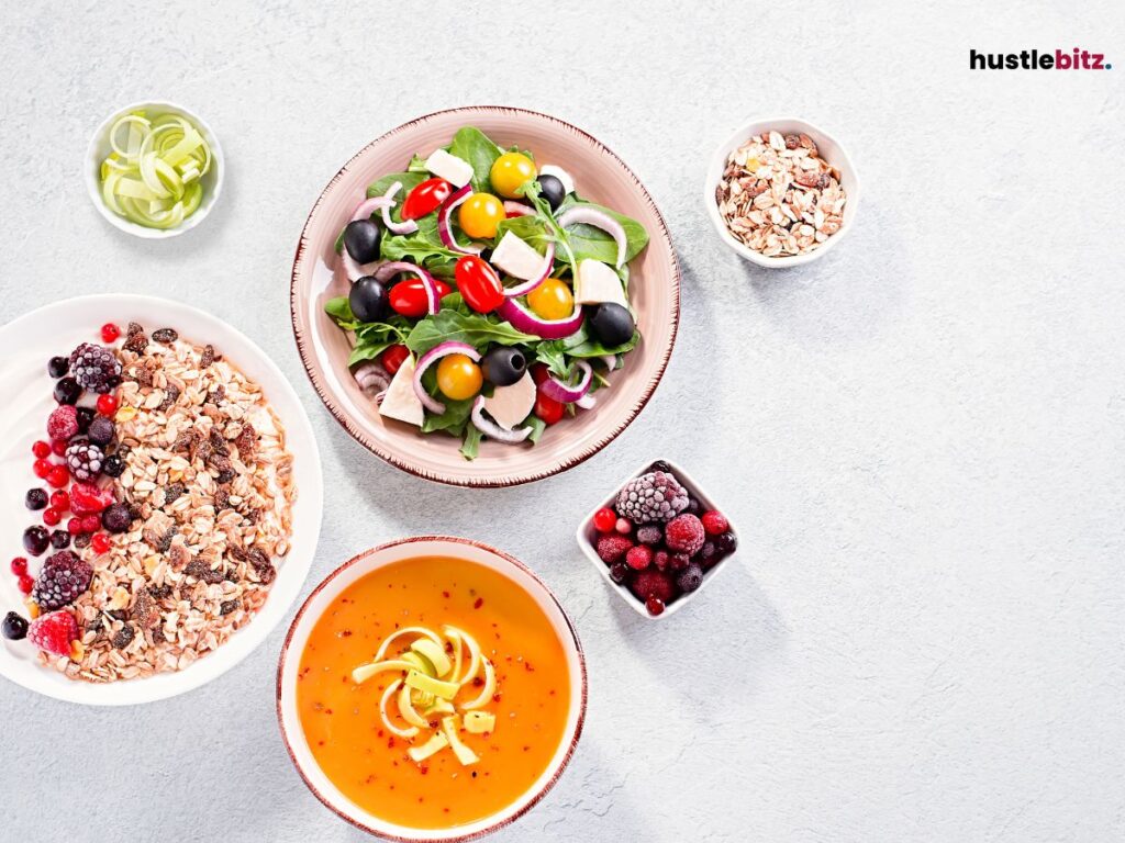 Colorful salad, cereal, and soup bowls arranged on a white table for a healthy meal.