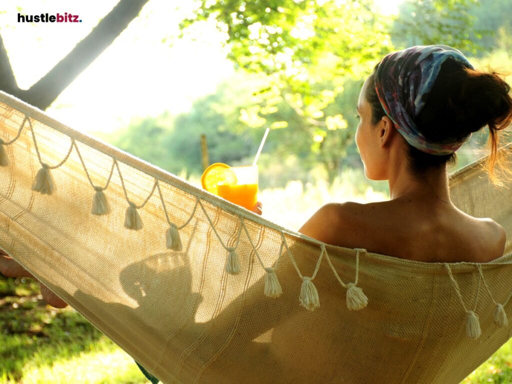 A woman sitting on a hammock holding fresh orange juice.
