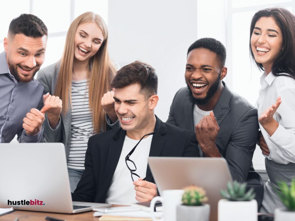 A group of people smiles while looking at the laptop