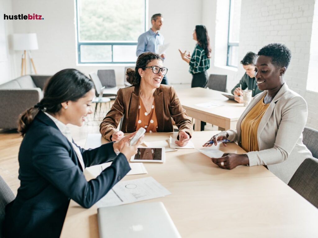 A group of colleagues smiling and working together in an office setting.