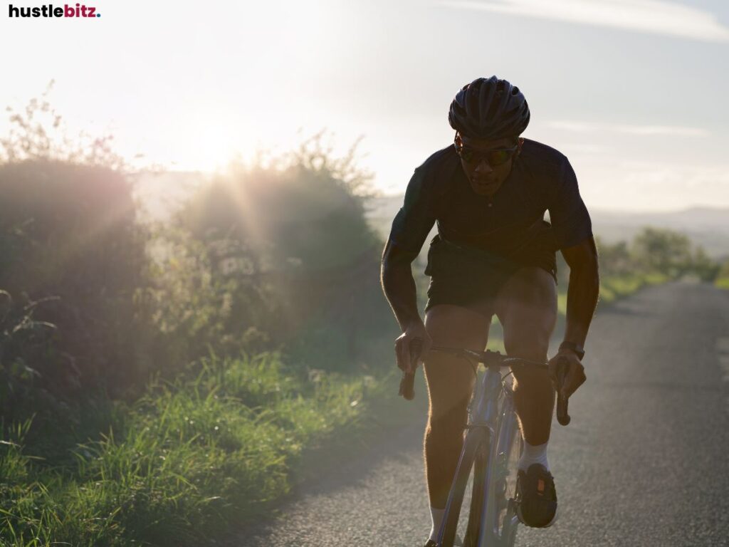 A cyclist pushing forward on a road, illuminated by soft sunlight.