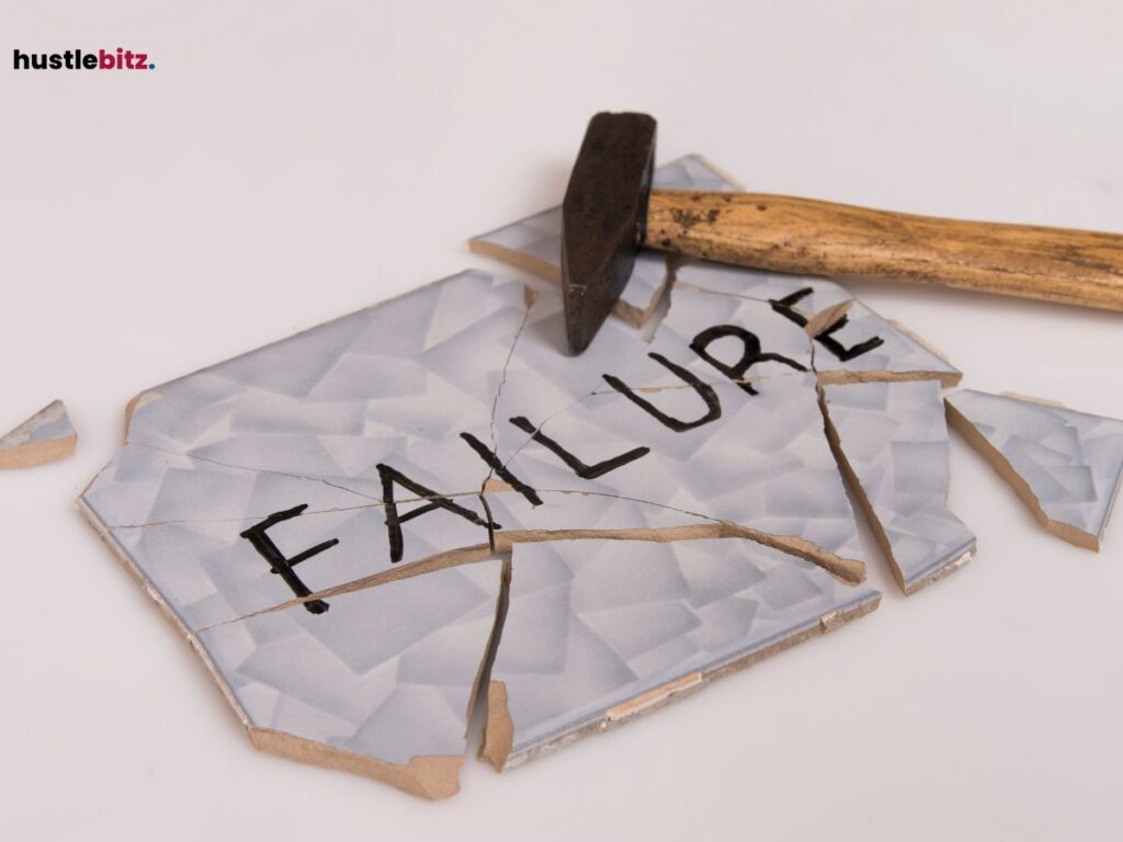 A hammer breaking a tile with the word "FAILURE" written on it.