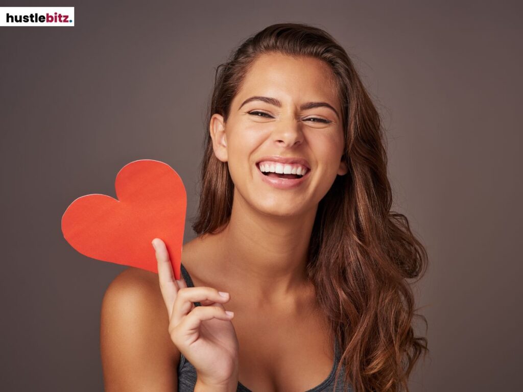 Woman holding a red heart, smiling brightly.