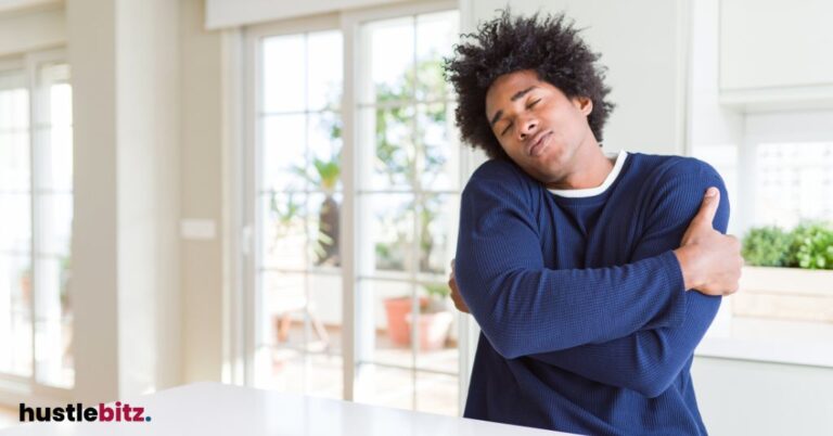 Man hugging himself, in a cozy home environment.