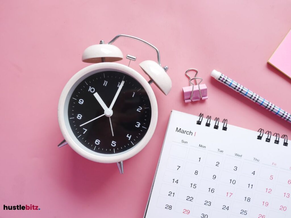 An alarm clock and a calender over a pink background.