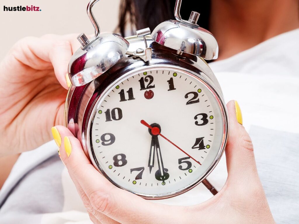 Close-up of a hand holding an alarm clock, showing the time approaching 7 o'clock.