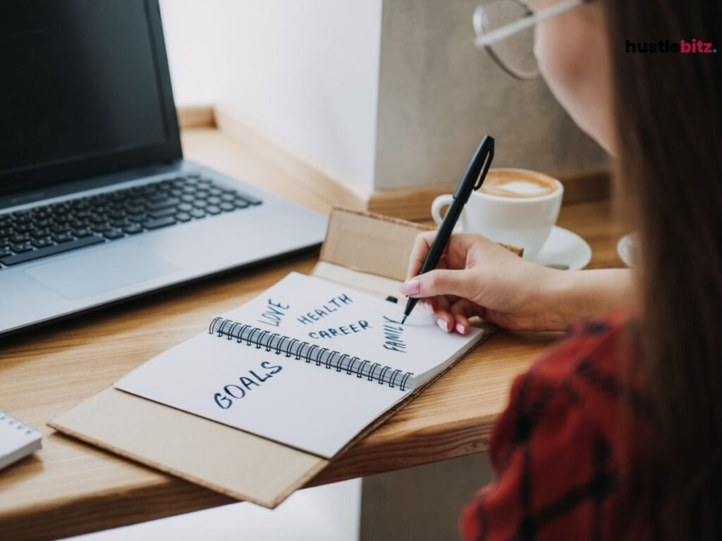 A woman doing writing and a laptop in the table